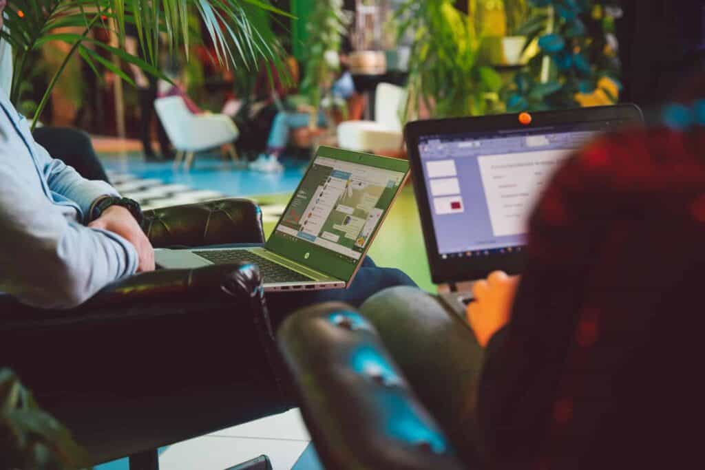 Person Sitting and Holding-Black and Silver Laptops